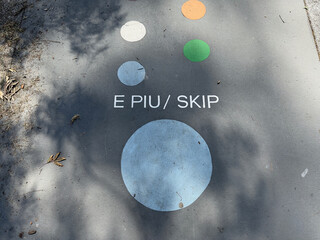 Markings on the tarmac of a playground have the words 'E Piu' and 'Skip'. Maori and English Language.New Zealand.