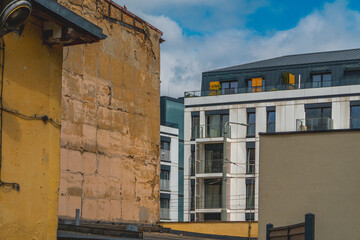 old residential buildings versus modern architecture of urban buildings. urban contrasts against the background of blue sky and white clouds