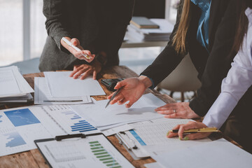 Businesswomen are having a discussion about financial charts and documents, pointing at graphics...