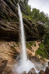 Obraz premium Pericnik waterfall is a beautiful drop from the mountain cliff, in Triglav National Park. Slovenian waterfall. Long for walking and trekking, enter inside the cave to admire it. Powerful and majesty.