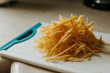 Freshly grated pile of cheddar cheese sits on cutting board