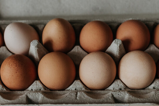 Close up overhead shot of fresh brown and beige eggs in egg carton