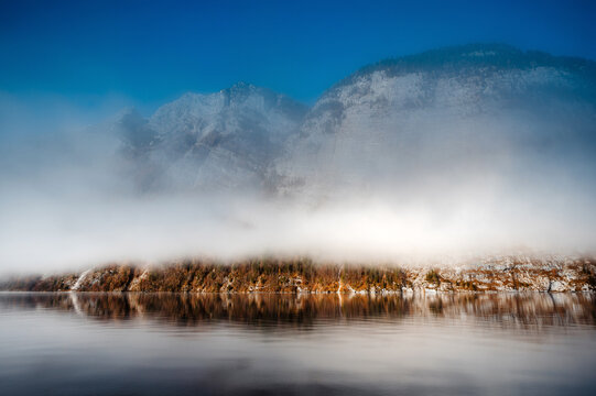Picturesque view of frozen lake surrounded by hills under cloudy sky