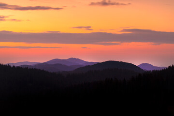Colorful Sunset Over Silhouetted Mountain Ranges. A breathtaking view of a vibrant sunset over a range of dark, silhouetted mountains.