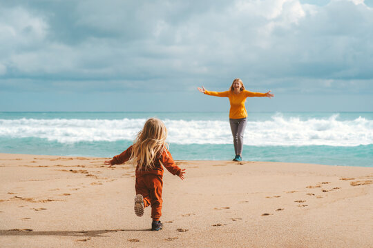 Daughter child running to her mother on sandy beach outdoor family travel lifestyle having fun together, summer vacations in Greece woman parent walking with kid