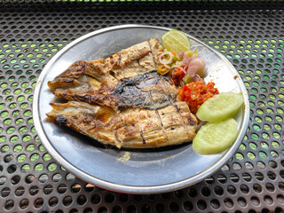 grilled milkfish served with chilli sauce, sliced cucumber and sliced lime