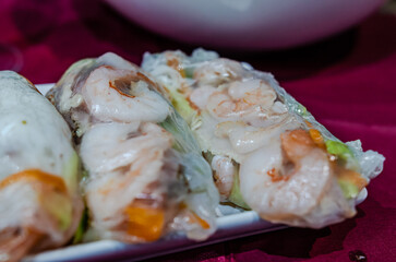 Fresh vietnamese shrimp spring roll served with peanut sauce on black plate. Close-up shot, vibrant colors, elegant plating, asian cuisine, restaurant setting, fine dining, appetizing mood, culinary