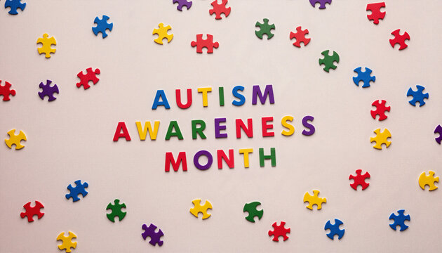 Colorful puzzle pieces surrounding "Autism Awareness Month" text on a neutral background, National Autism Awareness Month theme