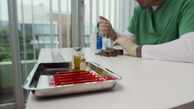 Cropped shot of male veterinarian using medical liquid-filled vial while examining python snakes health on clinic table