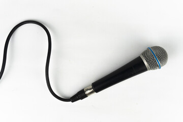 Top-down view of a black microphone on a white backdrop, with its cable forming a gentle curve...