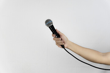 An arm holds a microphone, set against a stark white background, poised for speaking or singing.