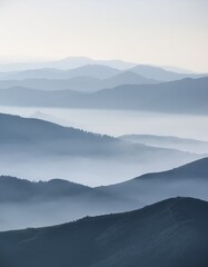 Fototapeta premium Misty mountain silhouette in soft gray tones offers tranquil, open text space. Minimalist and serene background. Ideal for quotes, messages, and calming designs