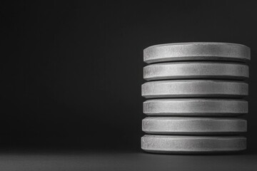 Stack of gray weight plates on dark background, showcasing stren