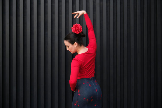 Young flamenco dancer performing with red rose and black background
