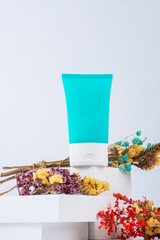 Cosmetic product in tube, bottle, lotion or serum and dried flowers with stylish props on white background. 