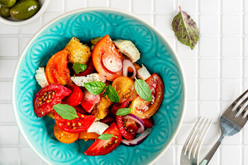 Panzanella made of toasted Ciabatta, red onions, tomatoes and basil. Traditional Italian cooking.