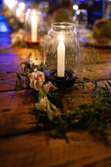 A decoration in the form of a lamp with a real candle inside on a wooden table.
