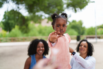 Little girl reaching out hand while playing with family in park