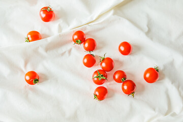Cherry tomatoes scattered on white fabric. Natural light highlights their vibrant color and texture, creating a fresh, minimalist food composition perfect for organic produce and healthy eating themes