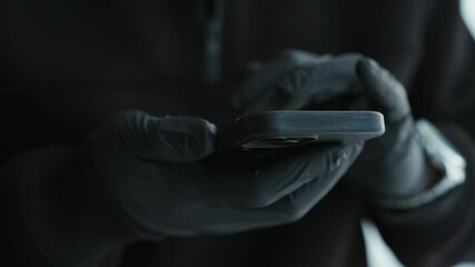 Phone theft.
Fingerprints on the phone screen.
Criminal in black gloves.
PIN code on your phone.
Telephone blocking.
A man enters a PIN code on his phone.