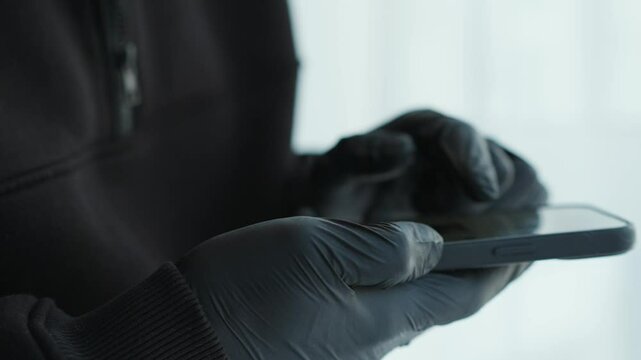 A man in black gloves clicks the phone in front of the camera.
A person wearing gloves touches a mobile phone so as not to leave fingerprints.
Fingerprints on the phone screen