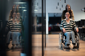 A joyful moment in a modern office. A woman in a wheelchair is pushed by a colleague, both smiling....