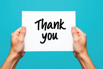 A Close-Up View of a Pair of Hands Holding a Thank You Sign Against a Bright Blue Background, Capturing a Gesture of Gratitude and Appreciation