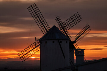 Sunset over the windmills of Campo de Criptana, casting a golden glow on the iconic landscape of Castilla-La Mancha, Spain, famously linked to Don Quixote