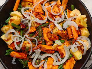 Vegan, vegetarian, seasonal, summer eating concept. Roasted vegetables in a cast iron on a light...