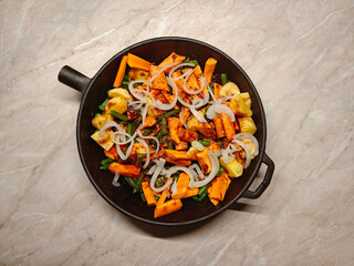 Vegan, vegetarian, seasonal, summer eating concept. Roasted vegetables in a cast iron on a light table. Top view flat lay background. Space for text