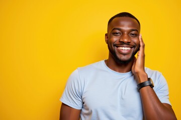 Fototapeta premium Cheerful Young African American Man Smiling Brightly Against a Vibrant Yellow Background, Showcasing His Joyful Personality and Positive Energy