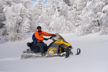 Athlete on a snowmobile moving in the winter forest in the mountains of the Southern Urals