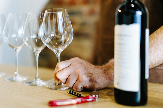 close-up of a hand holding a wine glass at a wine tasting event with a bottle and corkscrew