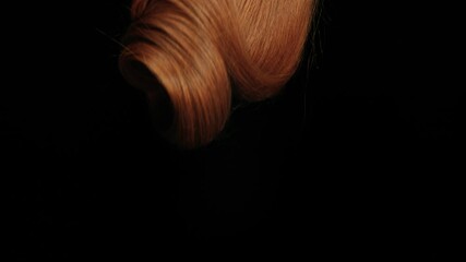 dropping long red or ginger hair in slow motion on black background
