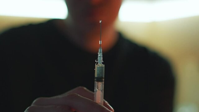 A man with a syringe in his hands in a dark room.
Drug addicted man with a syringe in his hands.
Drugs in a syringe.
Syringe with a needle close-up.
Drugs, syringe, heroin, drug addict