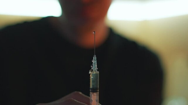 A man with a syringe in his hands in a dark room.
Drug addicted man with a syringe in his hands.
Drugs in a syringe.
Syringe with a needle close-up.
Drugs, syringe, heroin, drug addict