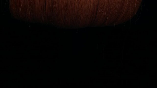 letting reddish blonde hair wig rolling down on black background and in slow motion