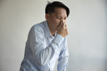 Middle aged old Asian man covering, pinching nose to prevent bad stinking smell, stinking odor, rotten smell with disgusting expression or reaction