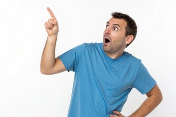 Fototapeta premium Surprised Man Pointing Upwards in a Blue T-Shirt Against a Plain Background