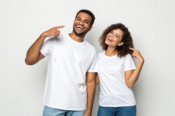 Obraz premium Joyful Young Couple Having Fun and Smiling Against a Light Background in Casual Attire