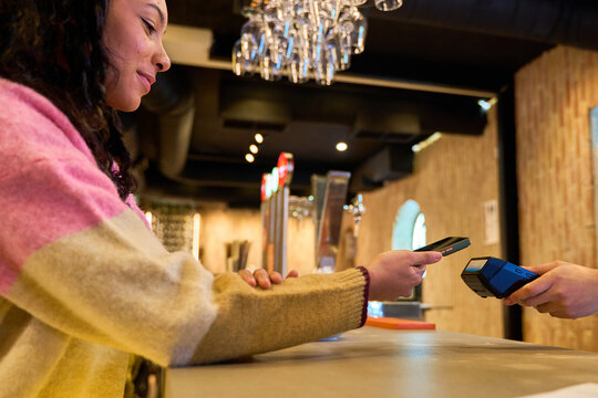 Customer paying with smartphone at bar counter with nfc technology