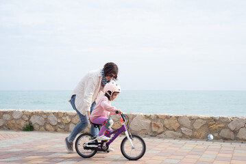 Fototapeta premium Mother teaching her 4 year old daughter to pedal a bicycle.