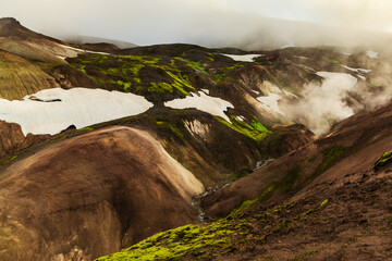 Lush green moss on Icelandic volcanic hills with melting snow patches