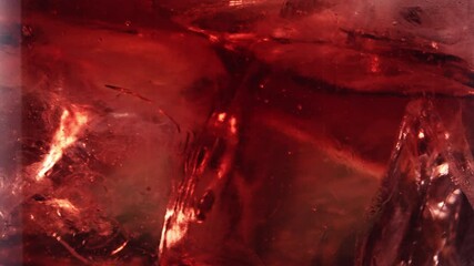 Close up shot of ice cubes rotating inside glass full of red juice liquid in slow motion - Powered by Adobe
