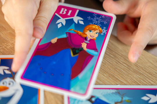 child, little girl excitedly exploring Disney Frozen playing cards, magical world favorite movie, childhood hobby, Frankfurt - November, 18, 2024
