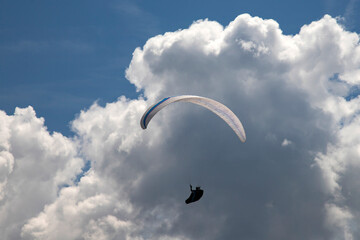 A man with a paraglider in front of a blue sky.
