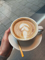A cup of coffee with beautiful latte art in a hand