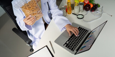 Dietitian analyzing pasta nutrition while using laptop