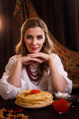beautiful russian girl with a stack of pancakes with red caviar on russian Maslenitsa.