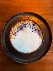 A creamy cocktail with frothy milk foam, decorated with delicate flower petals, offering both elegance and flavor.